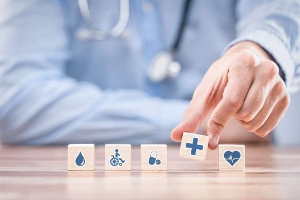 Un médecin en blouse bleue pointe des cubes en bois affichant des icônes médicales, représentant les garanties couvertes par une mutuelle santé.